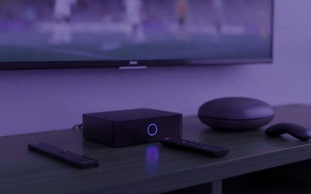 A streaming stick, a set-top box and a round streaming box with their remotes on a TV console