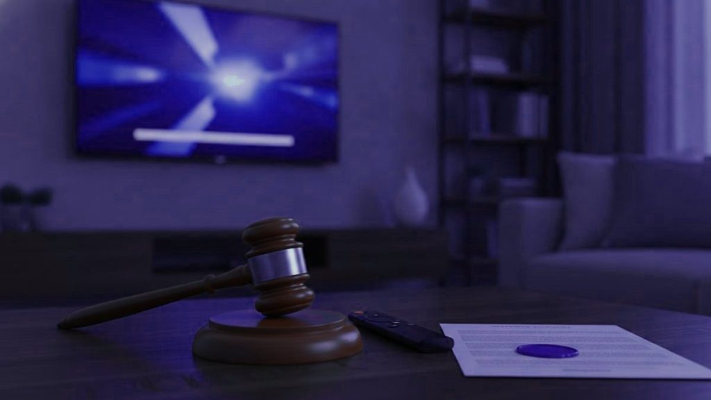 A judge gavel, a streaming remote and a sealed document on a coffee table in front of a TV
